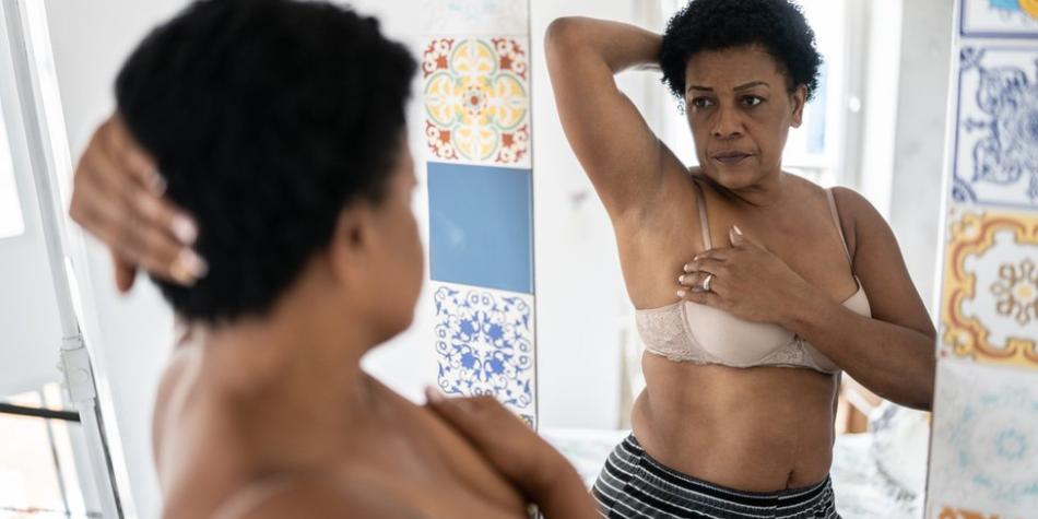 BBC Mundo: Una mujer se mira al espejo mientras inspecciona sus mamas.