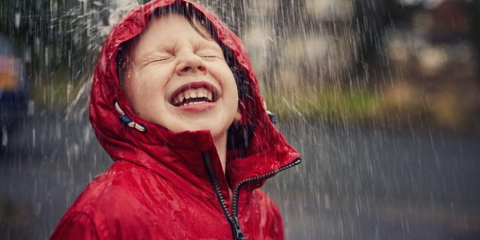 BBC Mundo: Un niño sonriendo bajo la lluvia.