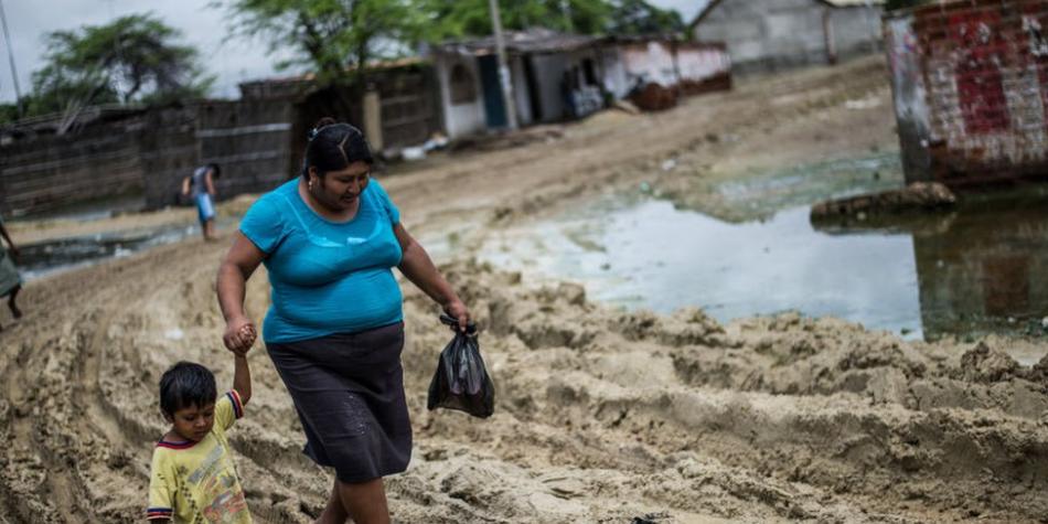 BBC Mundo: Una mujer con su hijo camina en Piura, después de las inundaciones de 2017.